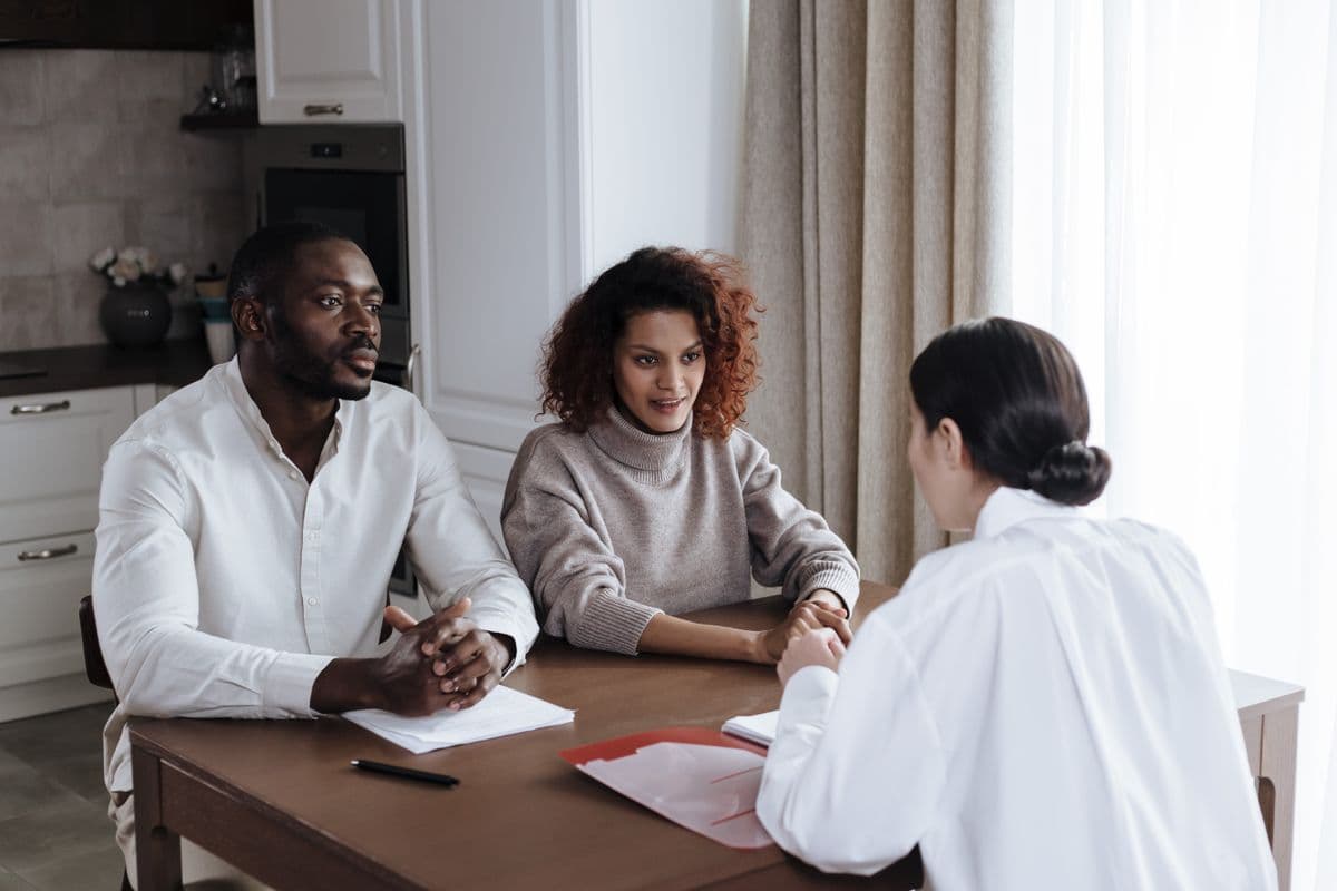 A worker meeting foster caregivers at their kitchen table